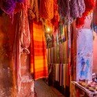 Vendita di sciarpe e tessuti colorati con vivaci pigmenti naturali in un Souk della Medina di Marrakech